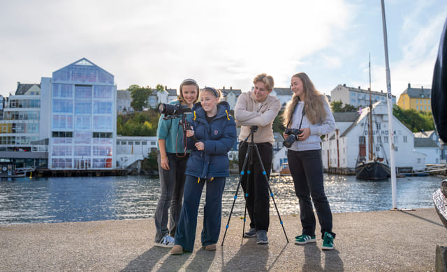 En gjeng elever står utenfor Akademiet VGS Ålesund med medieutstyr