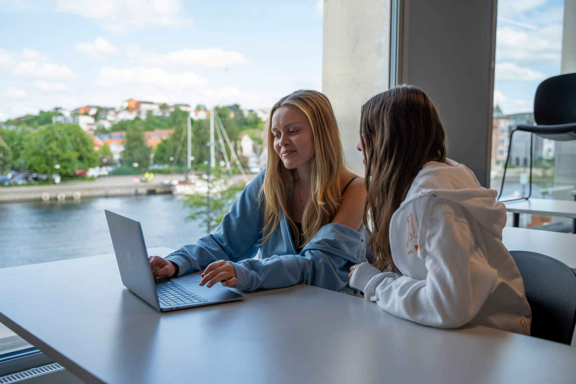 To elever sitter i klasserommet på Akademiet VGS Fredrikstad. Utsikt mot byen,