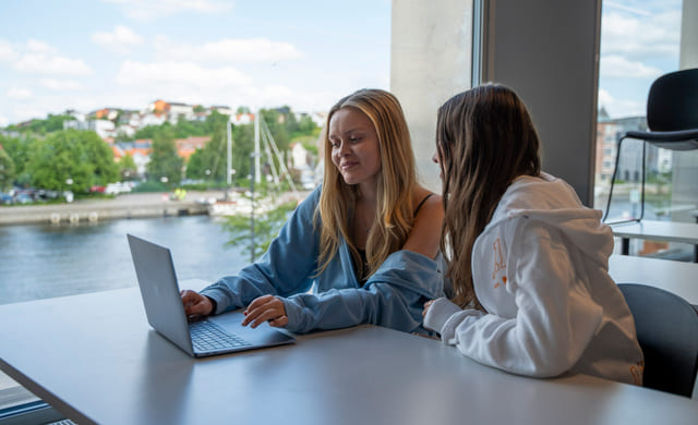 To elever sitter i klasserommet på Akademiet VGS Fredrikstad. Utsikt mot byen,