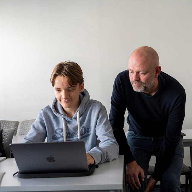 Mentor snakker med elev på informasjonsteknologi og medieproduksjon på Akademiet VGS Oslo.