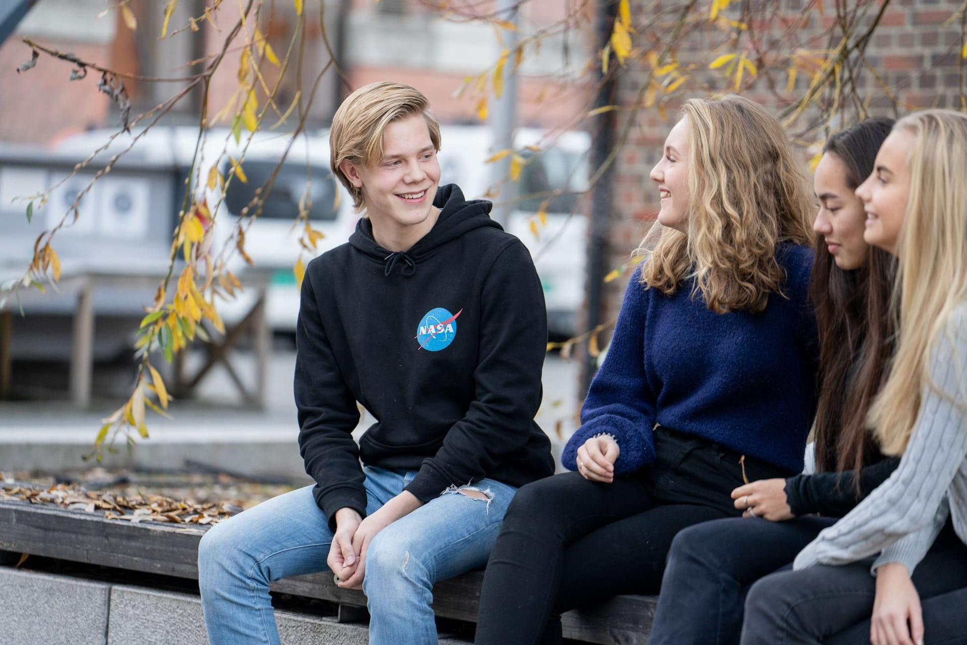 Fire elever fra Akademiet VGS Heltberg Drammen sitter på en benk