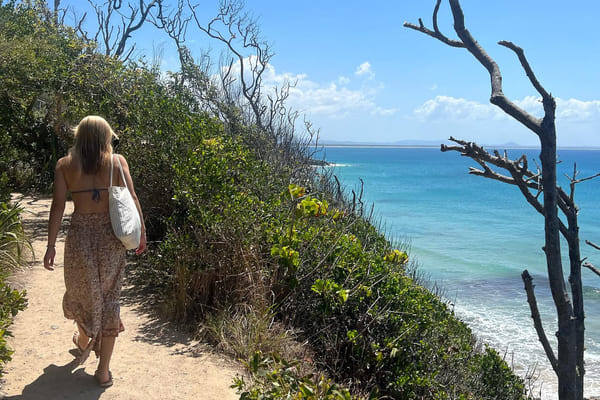 Jente går langs en ås ved en strand i australia