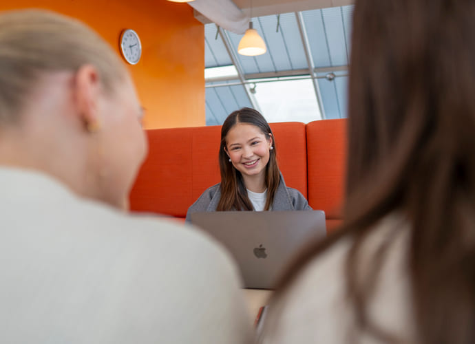 Tre privatister sitter sammen rundt et bord og leser med bøker og macbook.