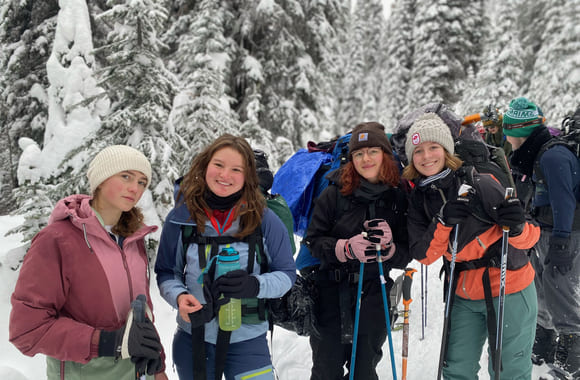 Johanna med flere venner smiler på tur i skogen i snødekte landskap.