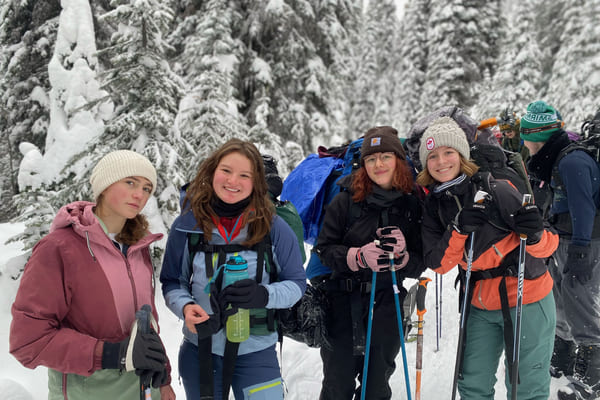 Johanna med flere venner smiler på tur i skogen i snødekte landskap.