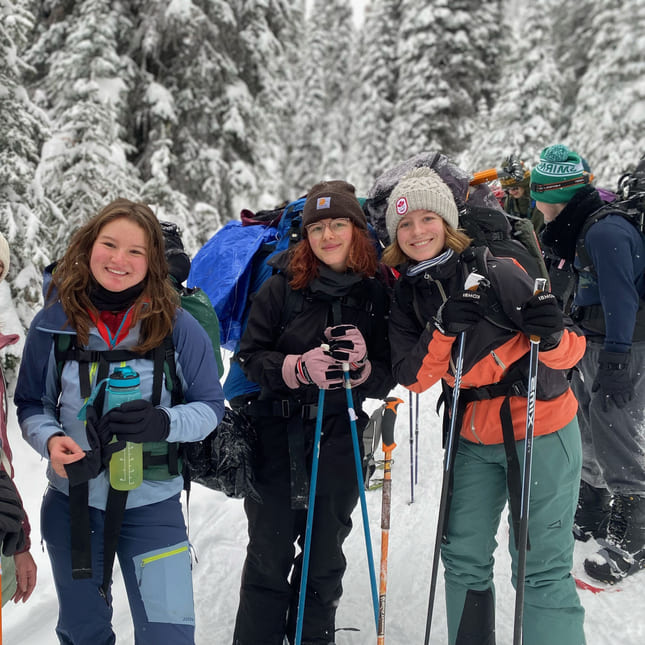 Johanna med flere venner smiler på tur i skogen i snødekte landskap.