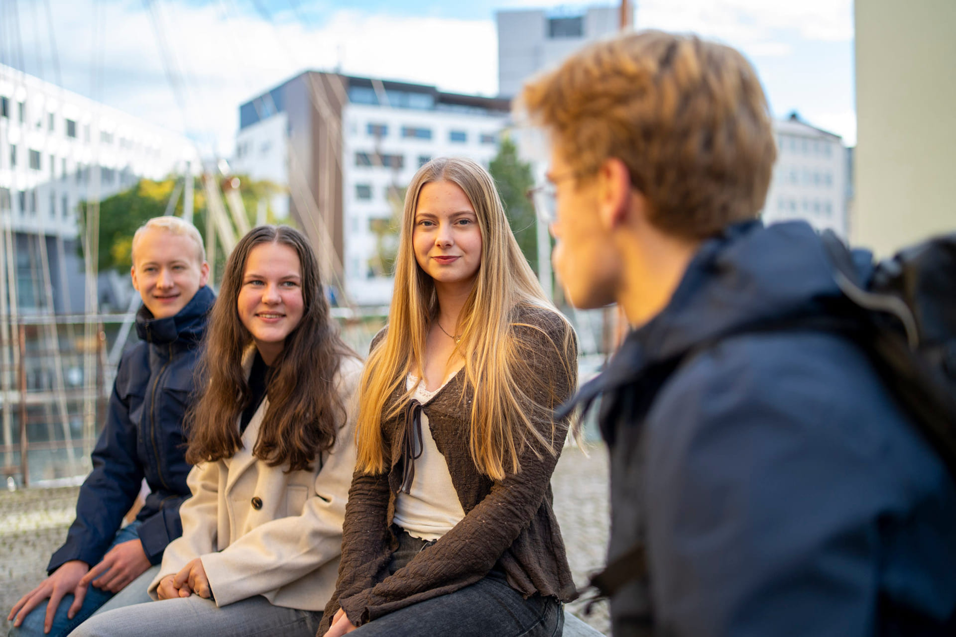 Fire elever snakker sammen utendørs.