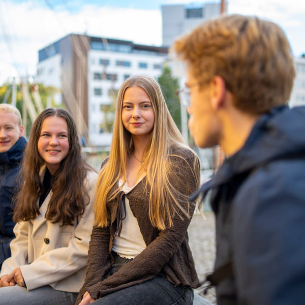 Fire elever snakker sammen utendørs.