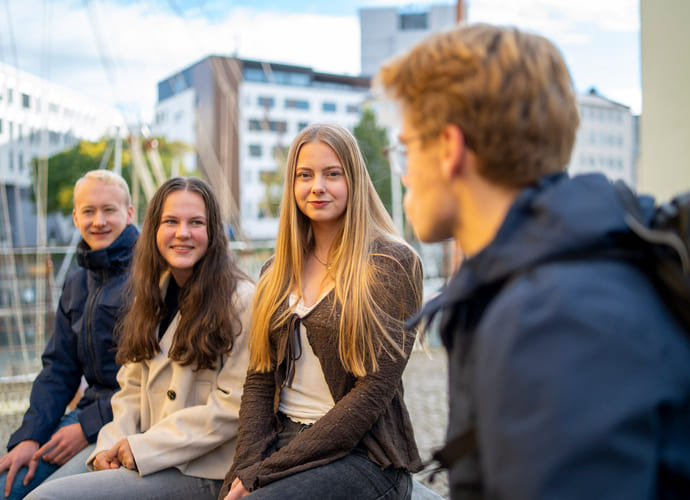 Fire elever snakker sammen utendørs.