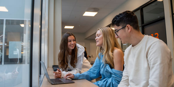 Tre elever sitter sammen og prater om skole på Akademiet Fredrikstad.