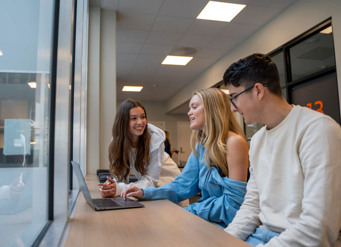 Tre elever sitter sammen og prater om skole på Akademiet Fredrikstad.